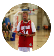 Man in red basketball jersey standing on indoor court.