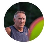 A man in a sleeveless shirt outdoors with a focused expression.