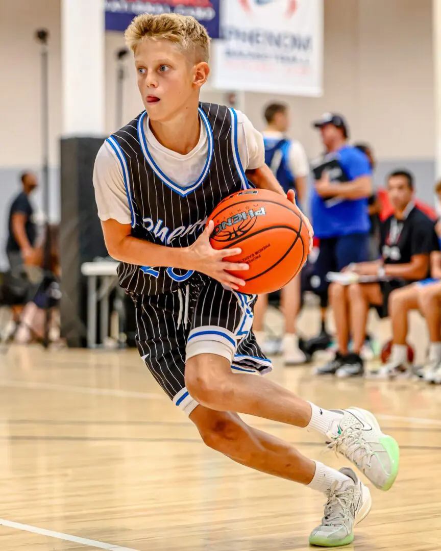 Young boy dribbling basketball in game.