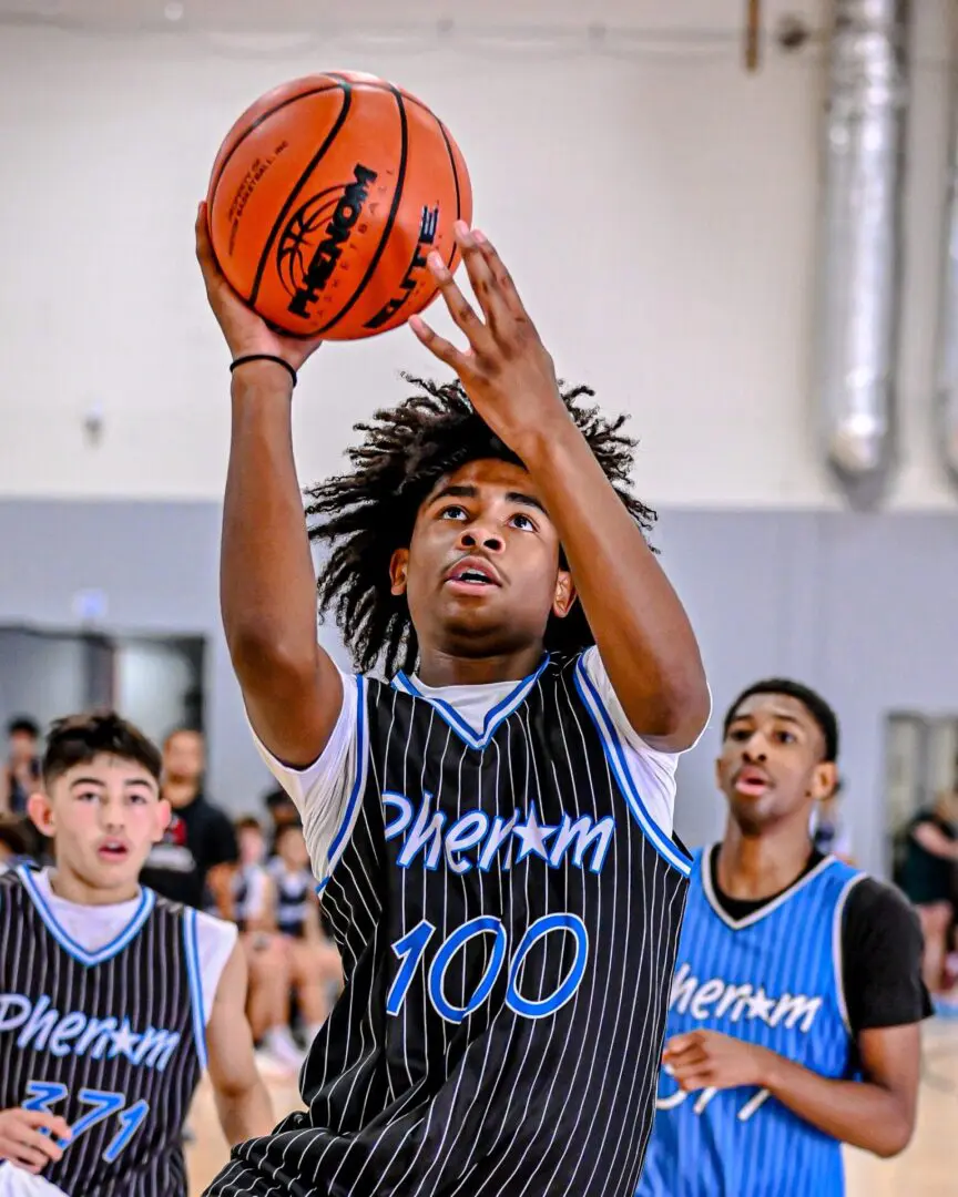 Teenager shooting basketball, Phenom 100 jersey.