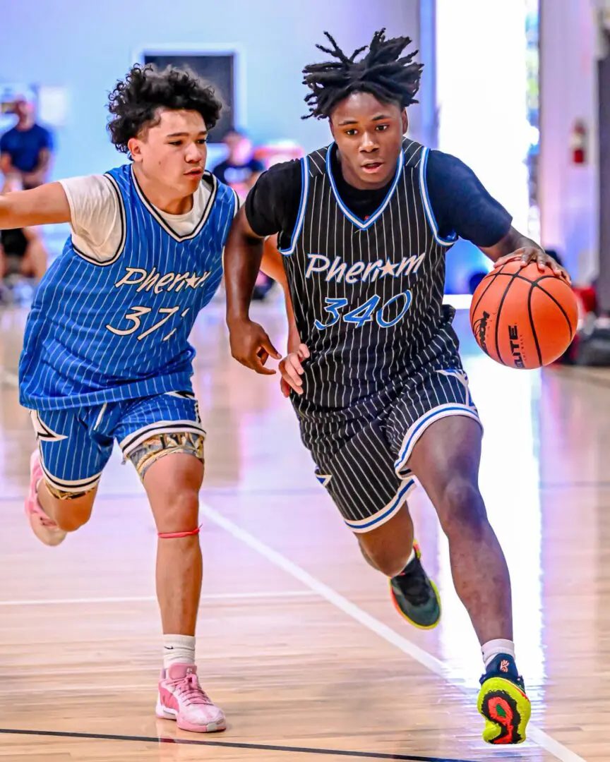 Two basketball players dribbling on court.