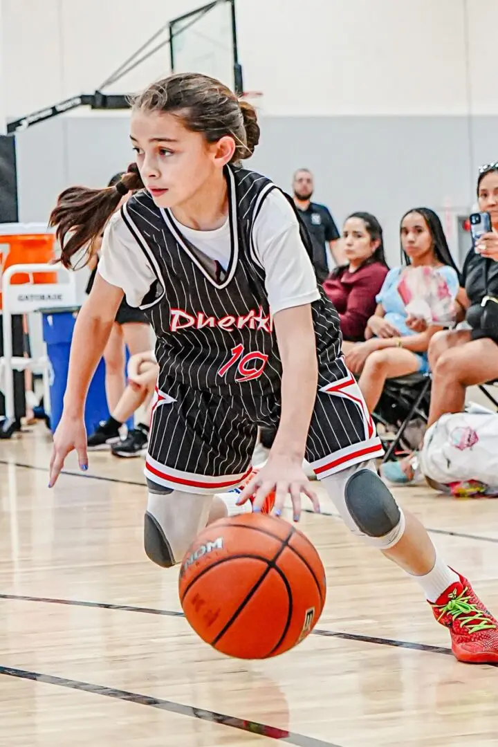 Girl dribbling basketball in game.