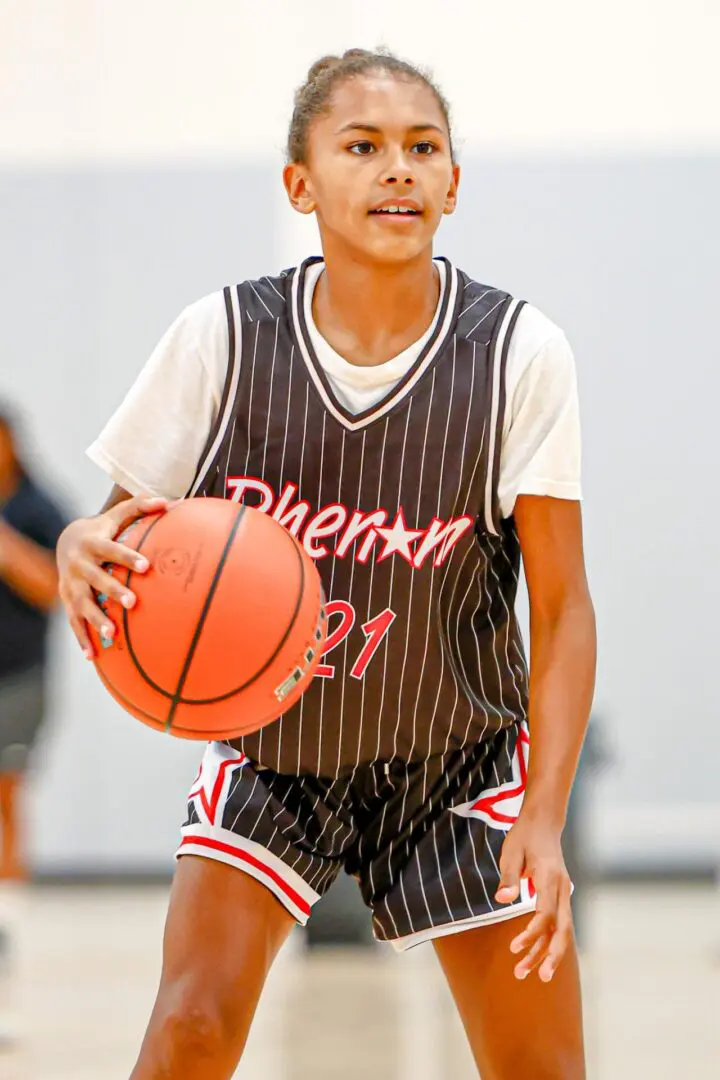 Girl in pinstripe jersey holding basketball.