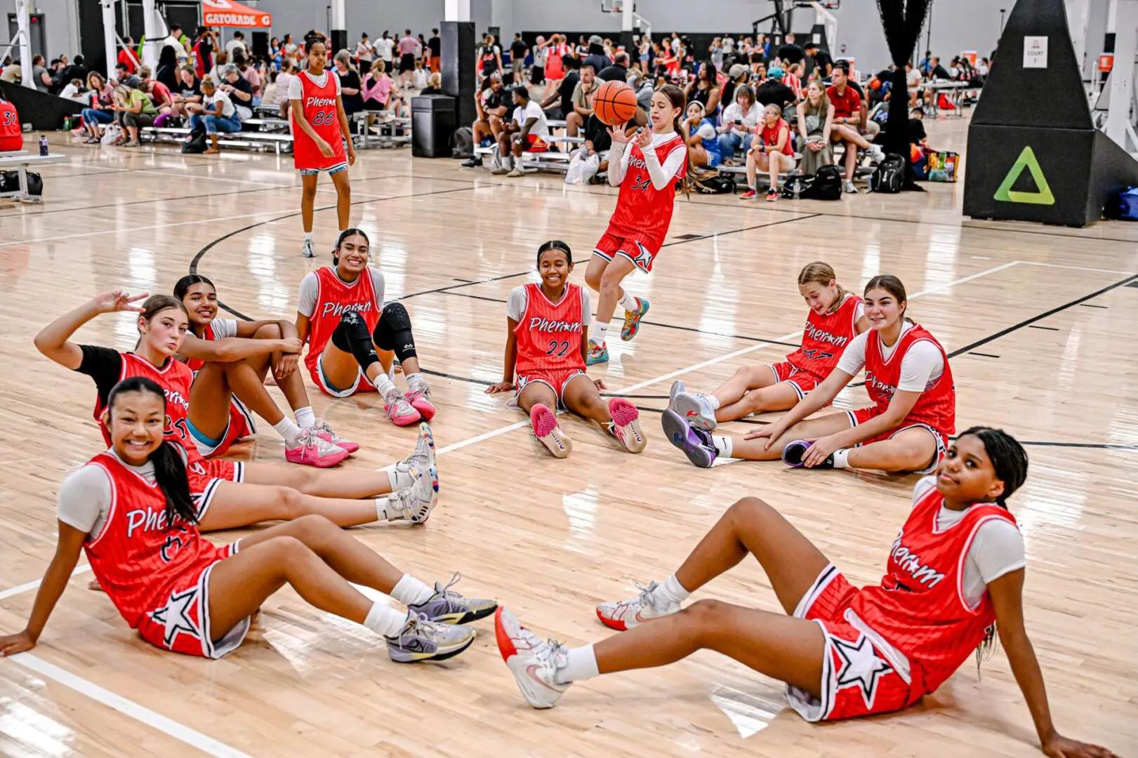 Girls basketball team resting on court.