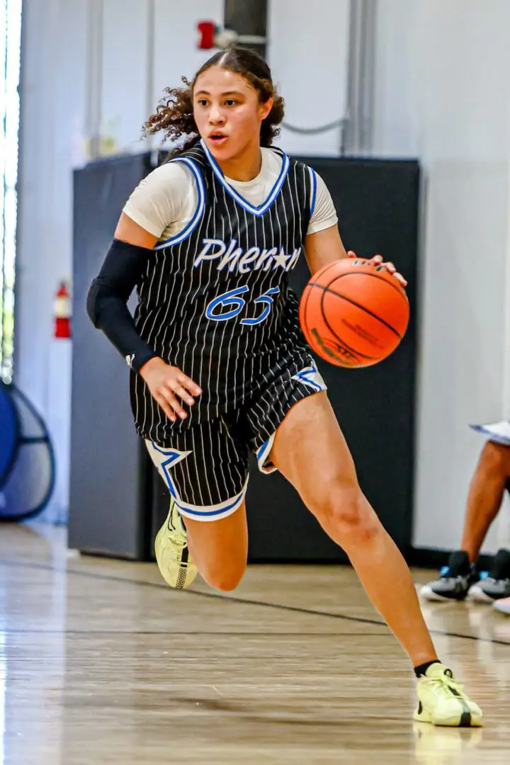 Female basketball player dribbling ball.