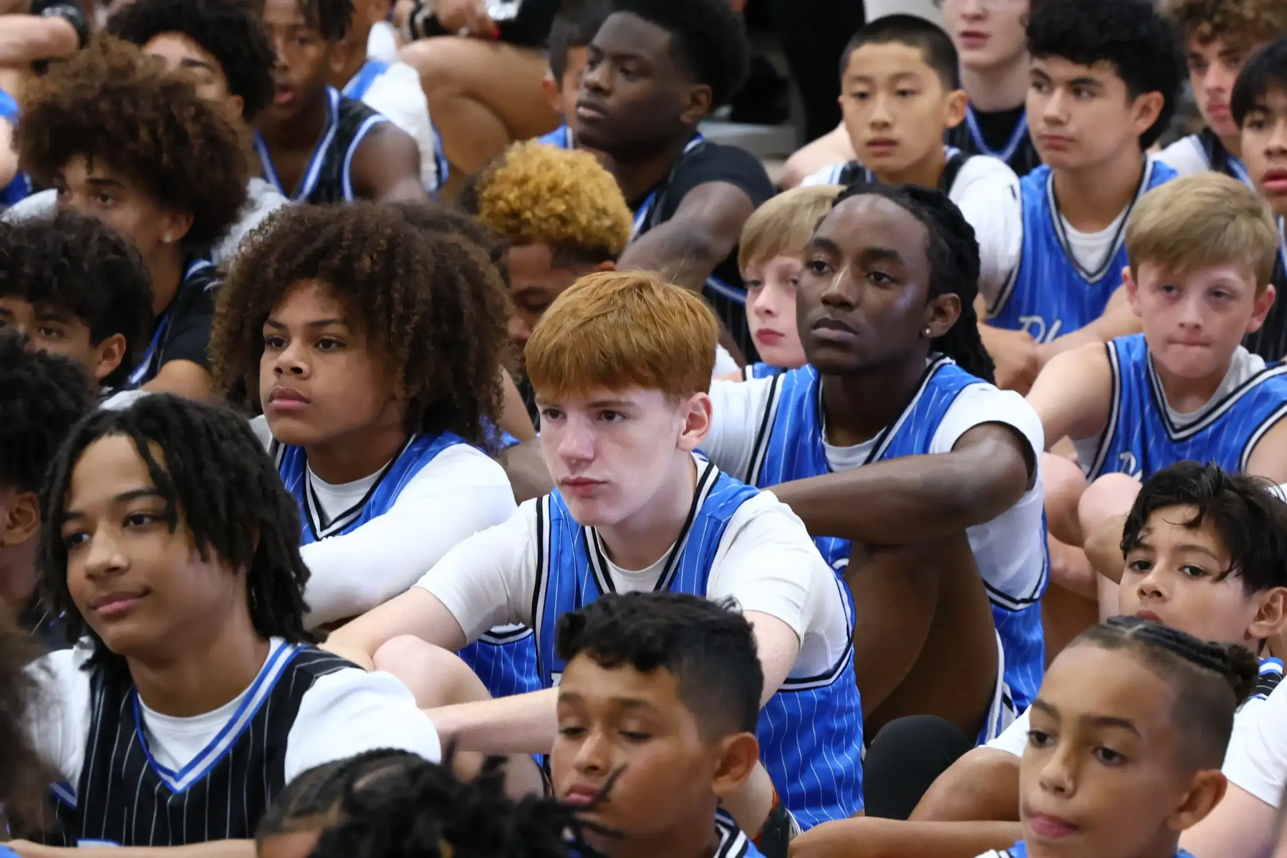 Group of young basketball players seated attentively.