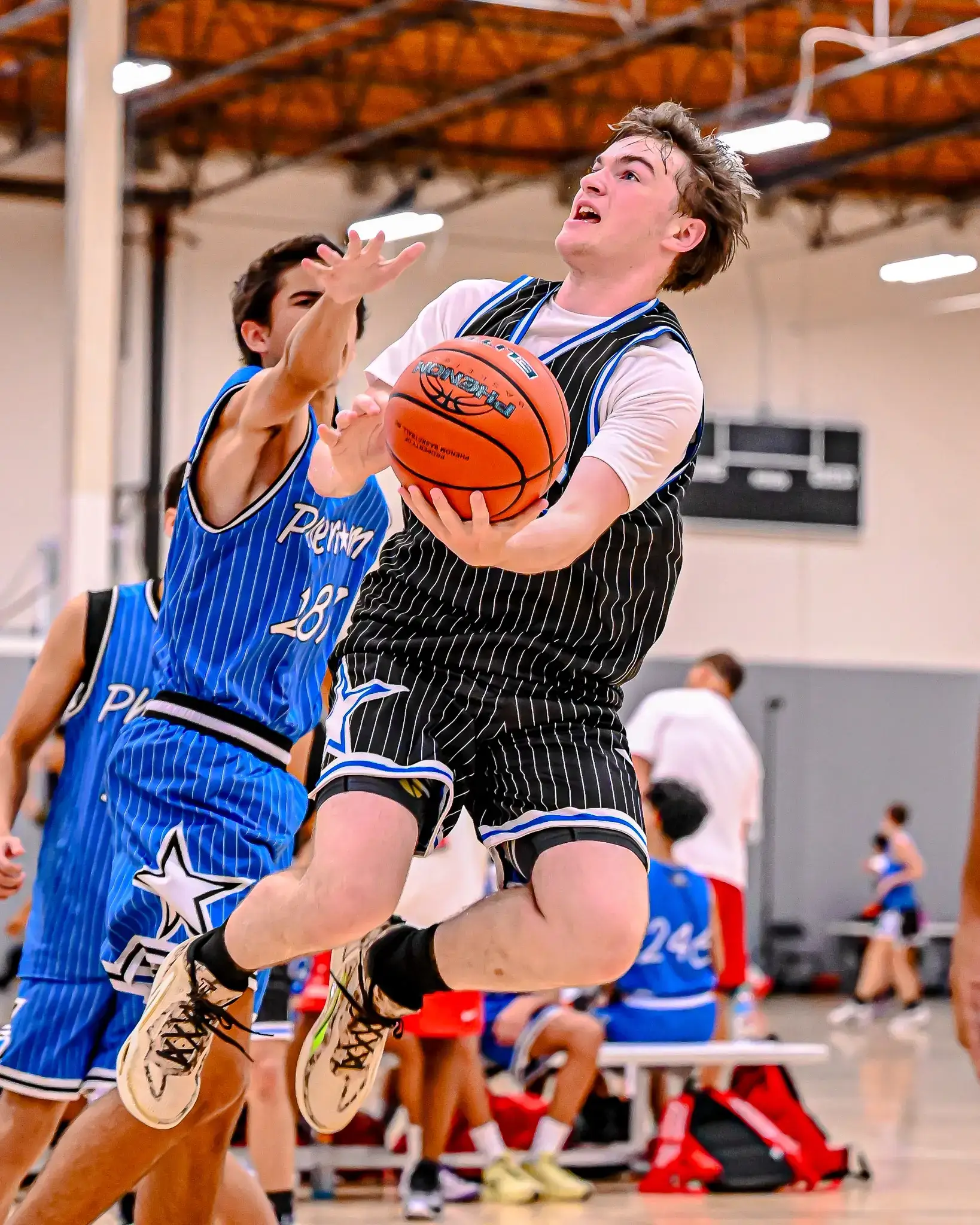High school basketball player driving to the basket during a game.