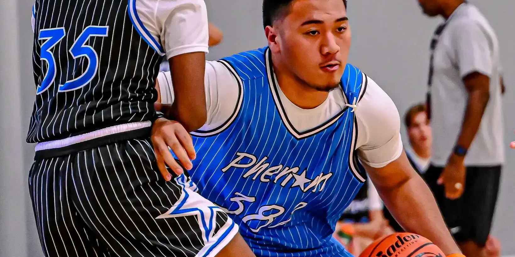 Basketball players in action during a game, one dribbling the ball.