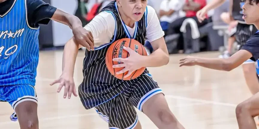 Young basketball player drives aggressively to the hoop amid defenders.